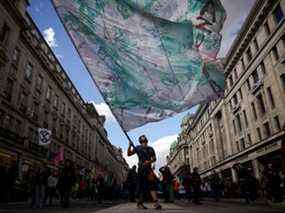 Un homme brandit un drapeau alors que des militants pour le climat d'Extinction Rebellion participent à une manifestation à Oxford Circus à Londres, en Grande-Bretagne, le 9 avril 2022.