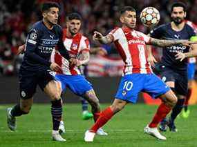 L'attaquant argentin de l'Atletico Madrid, Angel Correa, contrôle le ballon tout en étant défié par le défenseur portugais de Manchester City, Joao Cancelo (L), lors du match de football match retour du quart de finale de l'UEFA Champions League entre le Club Atletico de Madrid et le Manchester City FC au stade Wanda Metropolitano de Madrid, le 13 avril 2022.