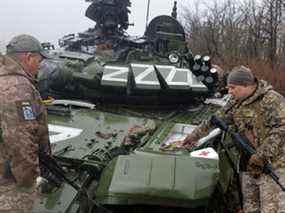 Des militaires ukrainiens inspectent un char russe endommagé, dans la région de Donetsk en Ukraine, le 13 avril.