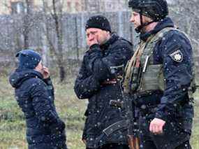 Les gens réagissent en se rassemblant près d'une fosse commune dans la ville de Bucha, juste au nord-ouest de la capitale ukrainienne Kiev, le 3 avril 2022. (SERGEI SUPINSKY/AFP via Getty Images)