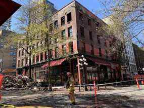 Un pompier marche devant l'hôtel Winters au 203, rues Abbott et Water vendredi.  L'hôtel de 1907 a subi un incendie dévastateur le 11 avril et est en cours de démolition.  Mais un corps a été retrouvé dans les ruines et la démolition a été temporairement interrompue vendredi.