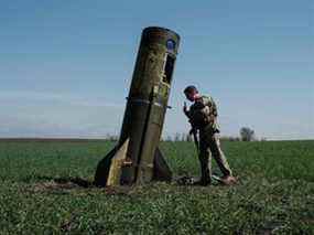 Un militaire ukrainien regarde l'étage d'appoint d'un missile balistique russe tombé dans un champ à Bohodarove, dans l'est de l'Ukraine, le 25 avril 2022.