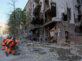 Des ouvriers communaux nettoient une zone autour d'un bâtiment détruit lors d'une frappe aérienne, au milieu de l'invasion russe de l'Ukraine, à Kiev, le vendredi 29 avril 2022.