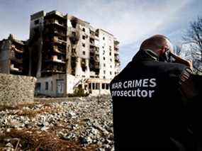 Un membre de l'équipe du procureur chargé des crimes de guerre parle au téléphone à côté de bâtiments qui ont été détruits par les bombardements russes, au milieu de l'invasion russe de l'Ukraine, à Borodyanka, dans la région de Kiev, en Ukraine, le jeudi 7 avril 2022.