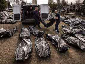 Des employés de cimetière déchargent les corps de civils tués à Bucha et dans les environs avant qu'ils ne soient transportés à la morgue d'un cimetière, le 7 avril 2022.