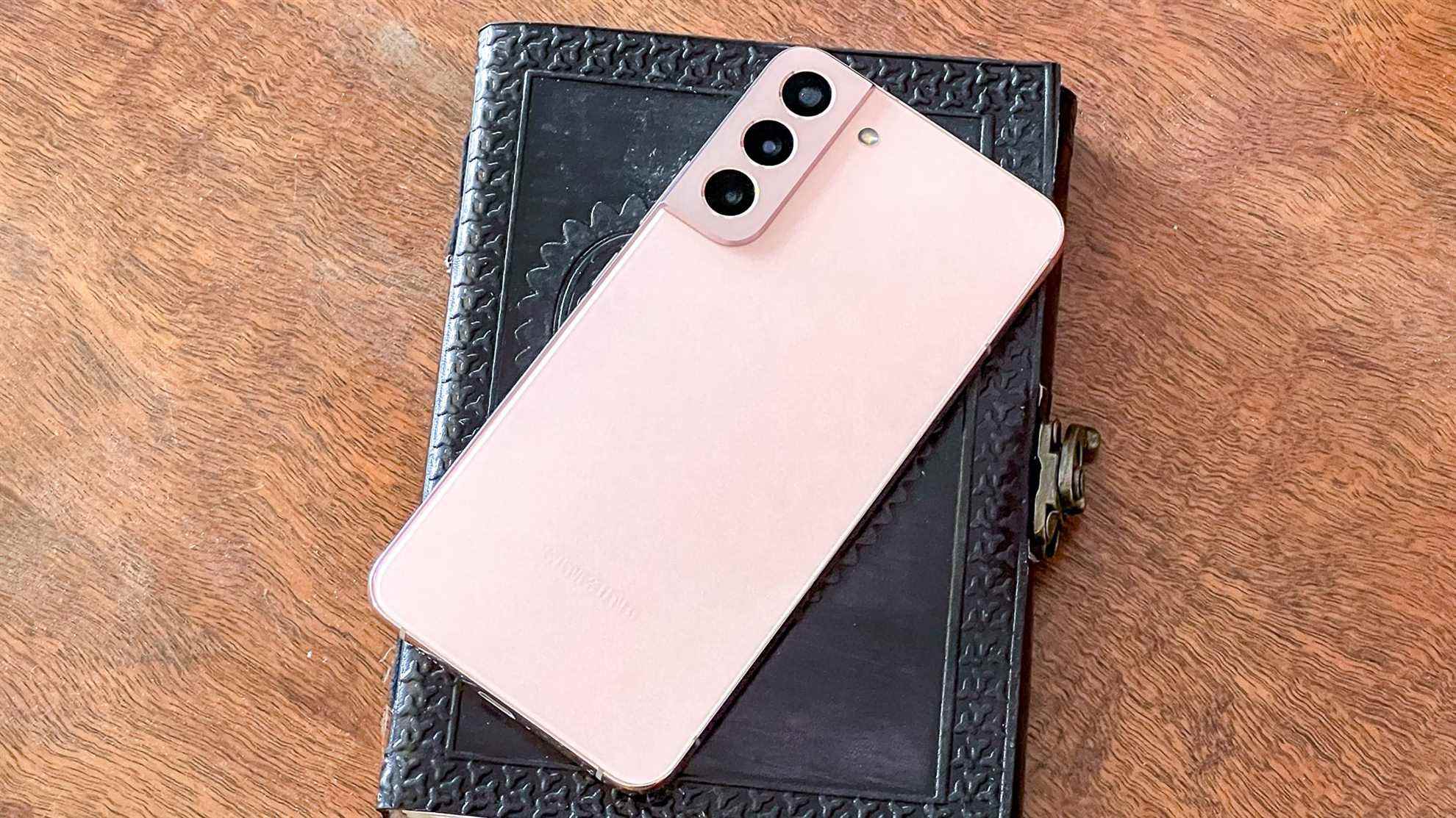 galaxy s22 plus en rose posé sur un livre relié en cuir