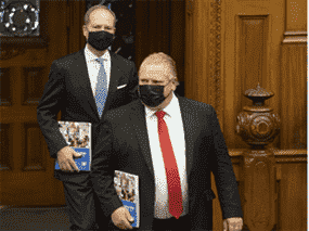 Le ministre des Finances de l'Ontario, Peter Bethlenfalvy (arrière) arrive à l'Assemblée législative de l'Ontario à Toronto avec le premier ministre Doug Ford (avant) pour présenter le budget provincial le 24 mars 2021.