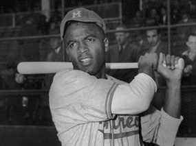 Joueur de baseball américain Jackie Robinson tenant une batte dans son uniforme des Royals de Montréal, l'équipe agricole des Brooklyn Dodgers, vers 1946.