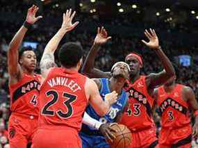 L'attaquant des Minnesota Timberwolves Jarred Vanderbilt (8) contrôle le ballon tout en étant défendu par le garde des Raptors de Toronto Fred VanVleet (23) et les attaquants Pascal Siakam (43) et Scottie Barnes (4) en première mi-temps à la Scotiabank Arena.