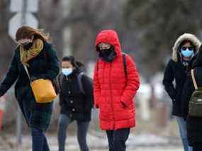 Les gens portent des masques en traversant une rue à Winnipeg mardi.