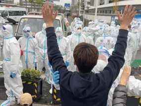 Un homme lève les mains alors qu'un policier portant une combinaison de matières dangereuses touche son bras, alors que les habitants protestent contre la transformation des complexes résidentiels voisins en installations d'isolement COVID-19, à Pudong, Shanghai, dans cette capture d'écran d'une vidéo signalée le 14 avril , 2022 et obtenu par Reuters le 15 avril 2022.