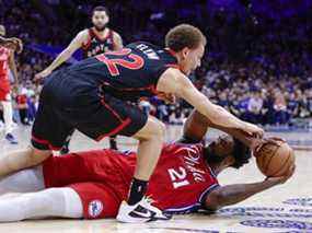 Joel Embiid des Philadelphia 76ers (à droite) se bat depuis le sol pour le ballon avec Malachi Flynn des Raptors au cours du premier quart du match 2 de leur série de premier tour de la Conférence Est au Wells Fargo Center le lundi 18 avril 2022 à Philadelphie.