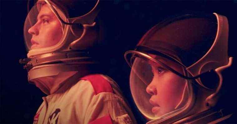 Guy and girl in astronaut suit glow with red hue.