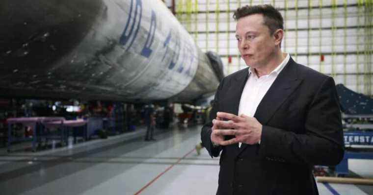 Man in suit stands in front of technology.