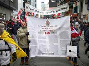 Des manifestants portant une copie de la Charte canadienne des droits et libertés défilent dans la rue Yonge alors que les camionneurs et leurs partisans continuent de protester contre les mandats de vaccination contre la maladie à coronavirus (COVID-19), à Toronto, Ontario, Canada, le 12 février 2022. REUTERS/Nick Iwanyshyn