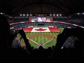 Les fans applaudissent alors qu'un drapeau canadien est déployé sur le terrain du Rogers Centre lors de la journée d'ouverture des Blue Jays, vendredi.  GETTY IMAGES