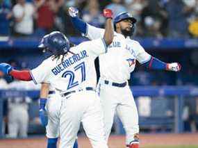 Le voltigeur droit des Blue Jays de Toronto, Teoscar Hernandez, célèbre avec le joueur de premier but Vladimir Guerrero Jr. après avoir frappé un circuit de trois points lors de la cinquième manche contre les Rangers du Texas au Rogers Centre de Toronto, le 8 avril 2022.