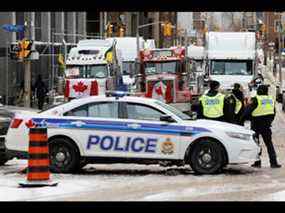 La police patrouille une barricade tandis que des véhicules bloquent les rues du centre-ville alors que les camionneurs et les partisans continuent de protester contre les mandats de vaccination contre la maladie à coronavirus (COVID-19) à Ottawa, Ontario, Canada, le 3 février 2022.