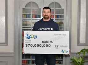 Dale McEwen est photographié avec son chèque de 70 millions de dollars sur la photo fournie par la Western Canada Lottery Corporation.