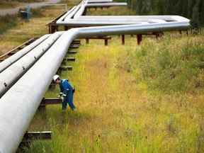 Un homme travaille à côté de pipelines à l'usine Foster Creek de Cenovus Energy en Alberta.