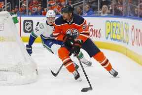 L'attaquant des Oilers d'Edmonton Evander Kane (91) cherche à faire une passe devant les défenseurs des Canucks de Vancouver Tyler Myers (57) au cours de la troisième période à Rogers Place vendredi.