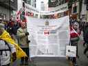 Des manifestants portant une copie de la Charte canadienne des droits et libertés défilent dans la rue Yonge alors que les camionneurs et leurs partisans continuent de protester contre les mandats de vaccination contre la maladie à coronavirus (COVID-19), à Toronto, Ontario, Canada, le 12 février 2022. REUTERS/Nick Iwanyshyn 