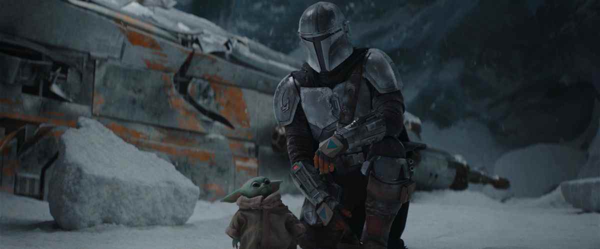 Le Mandalorien s'accroupit dans la neige à côté de Grogu dans la saison 1 de The Mandalorian