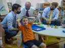 Le premier ministre Justin Trudeau, le ministre de l'Éducation Tom Osborne et le premier ministre de Terre-Neuve-et-Labrador Andrew Furey discutent avec des enfants au College of the North Atlantic à St. John's, T.-N.-L., le 28 juillet 2021. 