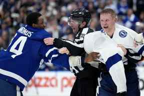 Les officiels séparent l'attaquant des Maple Leafs de Toronto Wayne Simmonds (24) et l'attaquant du Lightning de Tampa Bay Corey Perry (10) alors qu'ils se battent au cours de la troisième période, premier tour, match de hockey des séries éliminatoires de la Coupe Stanley de la LNH à Toronto, le lundi 2 mai 2022.