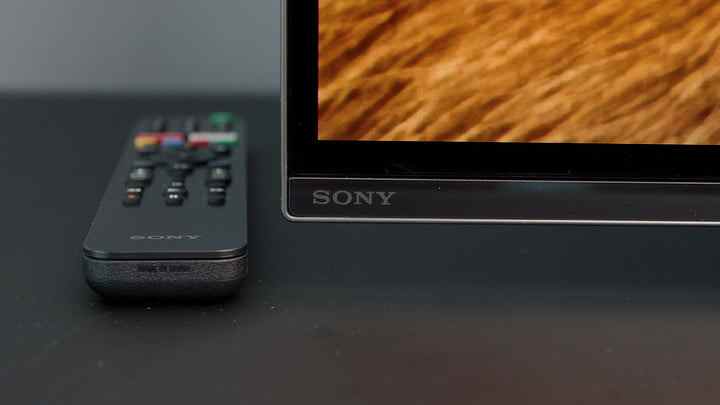 Le coin inférieur d'un Sony A8H OLED avec sa télécommande posée sur la table à côté. 