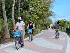 Des touristes en vélo le long de la plage de Miami, en Floride.