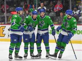 L'attaquante des Canucks d'Abbotsford Danila Klimovich (à gauche) et le défenseur Jack Rathbone (deuxième à partir de la gauche) célèbrent avec leurs coéquipiers après qu'un but a été marqué plus tôt cette saison.