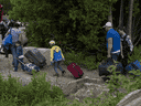 Une photo de 2018 d'une famille avec ses bagages en remorque au passage frontalier illégal de Roxham Road près de Perry Mills, New York.  Après avoir été fermé en mars 2020 en raison des craintes suscitées par la COVID-19, le passage est à nouveau occupé par la GRC. 