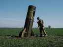 Un militaire ukrainien regarde l'étage d'appoint d'un missile balistique russe tombé dans un champ à Bohodarove, dans l'est de l'Ukraine, le 25 avril 2022. 