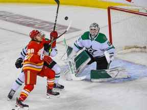 L'attaquant des Flames de Calgary Andrew Mangiapane se bat avec l'attaquant des Stars de Dallas Joel Hanley devant le gardien de but des Stars Jake Oettinger lors du match 7 de leur série éliminatoire de premier tour au Scotiabank Saddledome le dimanche 15 mai 2022.