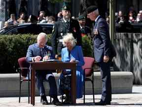 La duchesse de Cornouailles et le prince de Galles signent un livre au Monument commémoratif de guerre du Canada à Ottawa le 18 mai 2022.