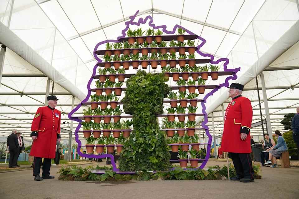 Les retraités de Chelsea Ted Fell (à gauche) et George Reid posent à côté du fleuriste Simon Lycett's The Queen's Platinum Jubilee, un présentoir en métal violet en forme de profil de la reine Elizabeth II contenant 70 pots en terre cuite jetés à la main, un pour chaque année du règne de la reine, et chacun planté d'un muguet, lors de la journée de presse RHS Chelsea Flower Show, au Royal Hospital Chelsea, Londres.  Date de la photo : lundi 23 mai 2022. (Photo de Yui Mok/PA Images via Getty Images)