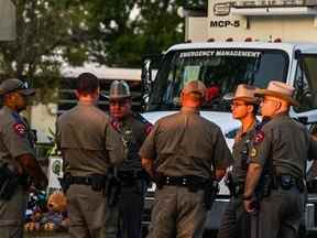 Des policiers parlent près d'un mémorial de fortune pour les victimes de la fusillade à l'extérieur de l'école élémentaire Robb à Uvalde, Texas, le 27 mai 2022.