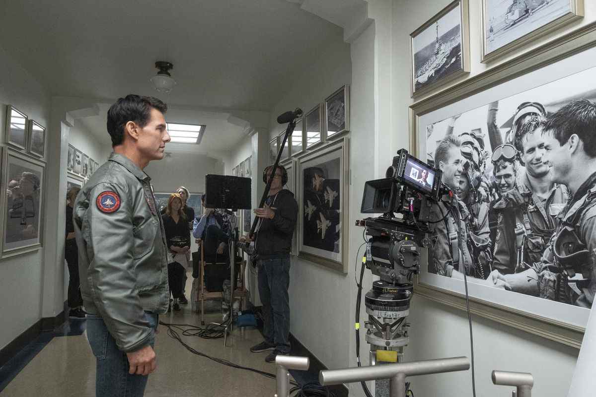 Une photo des coulisses de Tom Cruise debout devant un mémorial à l'école Top Gun dans Top Gun: Maverick.