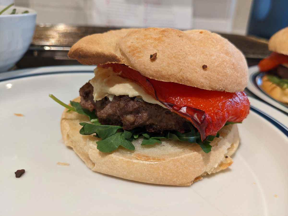 Une image du burger Hummus A Tune du livre de cuisine de Bob's Burger, avec du poivron rouge et du houmous.