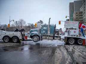 Une plate-forme Freedom Convoy est remorquée dimanche alors que les travailleurs de la ville restaurent la zone autour de la Colline du Parlement à la normale.