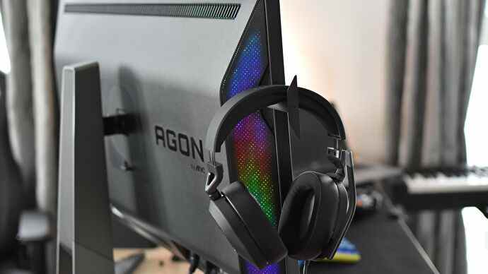 Un casque reposant sur l'un des crochets escamotables du moniteur Porsche Design AOC Agon Pro PD32M.