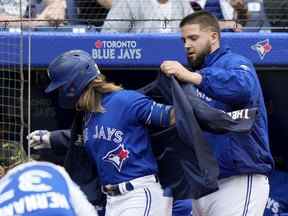 Le lanceur partant des Blue Jays Alek Manoah met la veste du coup de circuit à son coéquipier Bo Bichette après son circuit en solo lors de la quatrième manche de baseball interligue de la MLB contre les Reds de Cincinnati, à Toronto, le samedi 21 mai 2022