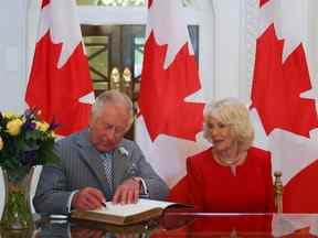 Le prince Charles, prince de Galles accompagné de Camilla, duchesse de Cornouailles, signe un livre d'or à la Maison du Canada à Londres le 12 mai 2022.