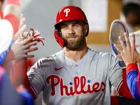 Le frappeur désigné des Phillies de Philadelphie Bryce Harper échange des high-fives dans l'abri après avoir marqué un point contre les Mariners de Seattle lors de la septième manche au T-Mobile Park.