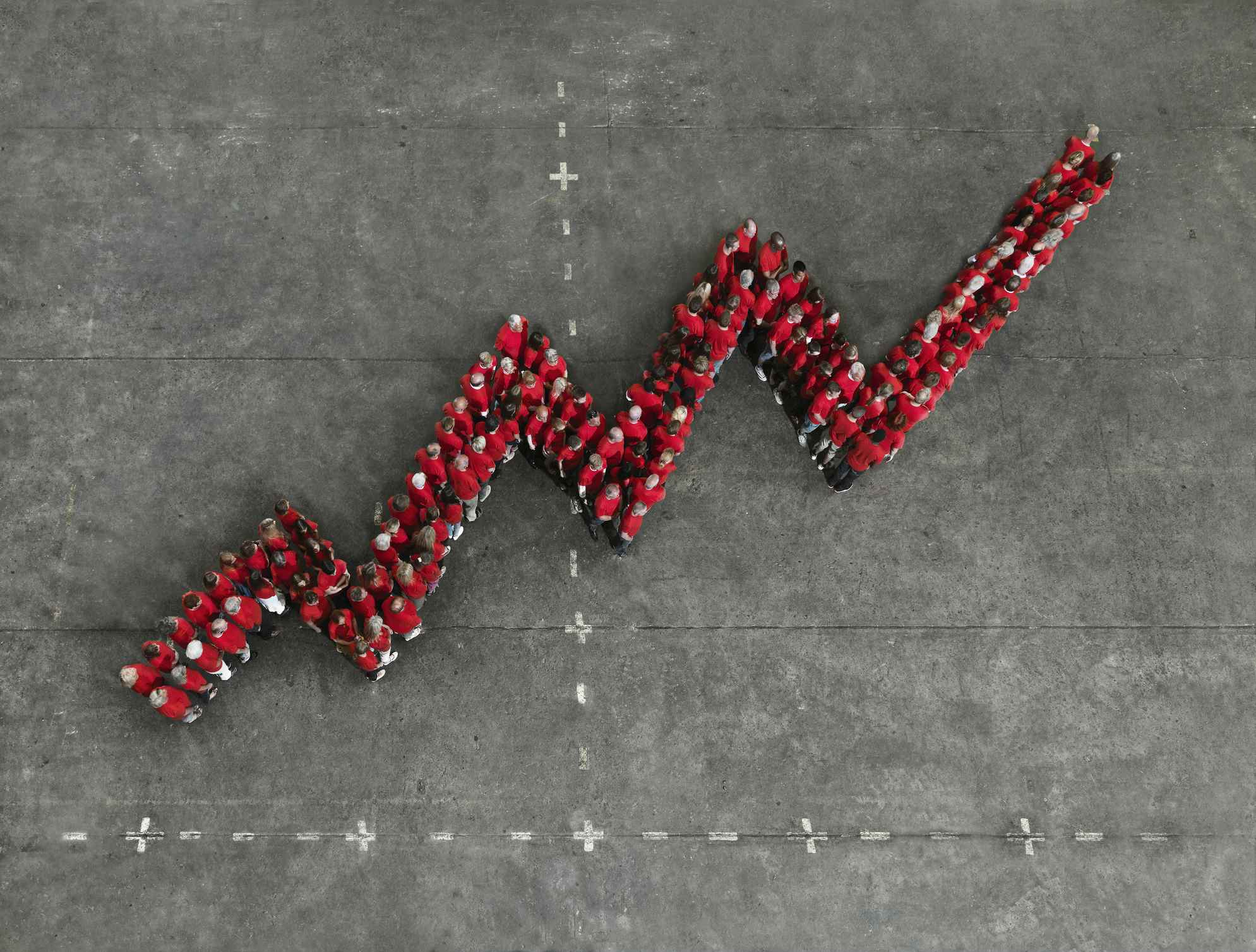 Une foule de personnes portant des chemises rouges, formant un graphique, symbolisant les opérations de produits et la contribution à la croissance axée sur les produits