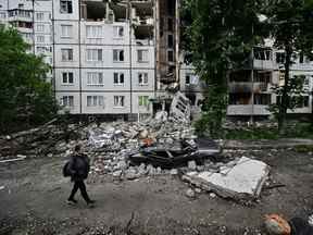 Une femme passe devant un immeuble résidentiel fortement endommagé dans le district de Saltivka, au nord de Kharkiv, le 29 mai 2022, au milieu de l'invasion russe de l'Ukraine.