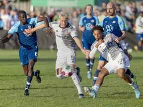 Le Toronto FC Lucas Macnaughton (au centre) et Kosi Thompson se battent pour le ballon avec HFX Wanderers Mour Samb lors du quart de finale du Championnat canadien au Wanderers Ground à Halifax hier soir.