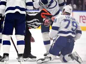 L'attaquant du Lightning de Tampa Bay Ross Colton (79 ans) est examiné par l'arbitre Dan O'Rourke (9 ans) après avoir été blessé par un coup sûr de l'attaquant des Maple Leafs de Toronto Kyle Clifford lors du premier match.