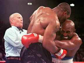 L'arbitre Lane Mills (à gauche) intervient alors qu'Evander Holyfield réagit après que Mike Tyson se soit mordu l'oreille au troisième tour de leur combat de championnat des poids lourds WBA au MGM Grand Garden Arena de Las Vegas.  Holyfield a gagné par disqualification après l'incident mordant.